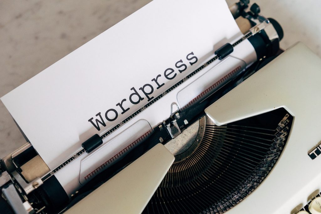 Eine Schreibmaschine mit einem eingespannten Blatt Papier auf dem das Wort WordPress geschrieben steht.